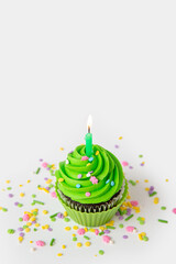 Colorful cupcake with green frosting and candle for special celebration
