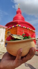 Bright red Tripura Sundari Temple, Udaipur, Tripura, India. Hand holds puja offerings.