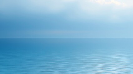 Obraz premium A serene landscape photograph depicts a tranquil ocean scene under a pale blue sky with subtle cloud formations on a calm day.