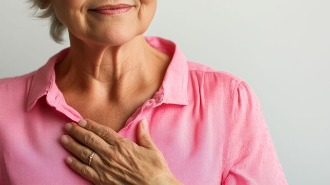 Elderly woman expresses emotion with a hand on her chest in a neutral setting indoors