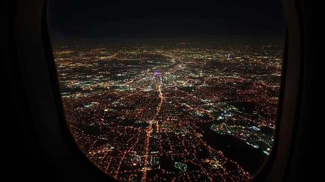Aerial night view of city lights viewed from airplane window