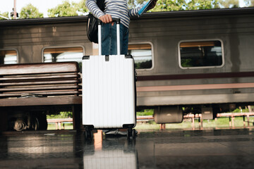 Stylish young woman traveling at train station with suitcase, traveling alone on vacation or...