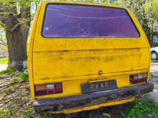 Yellow van with red window and license plate. The van is parked in a grassy area.