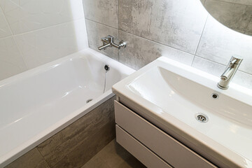 Clean bathroom featuring a white bathtub and sink, accented by gray and white tiles, and modern...
