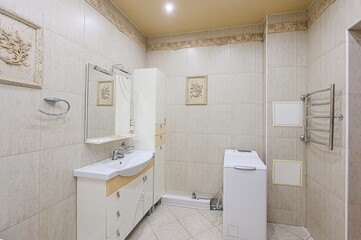bright bathroom features a corner bathtub, a vanity with mirror, and a tall cabinet. The walls are...