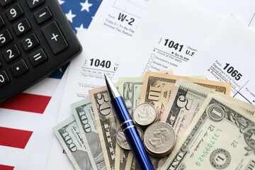 Fototapeta premium American US dollars money bills and coins with pen and calculator on IRS tax form blanks
