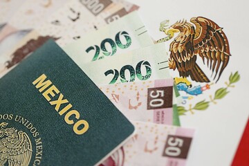 Mexican pesos money bills in big amount and passport lies on Mexico flag close up