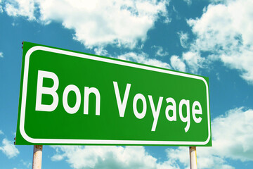 Bon Voyage Green Road Sign with clouds sky background
