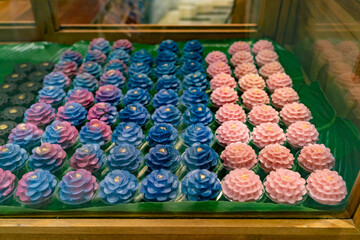 Display of intricately crafted Thai desserts called Khanom Chor Muang. These are traditional Thai desserts made to resemble flowers, using natural food coloring and shaped to look like rose flower.