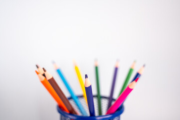 Colored pencils in a stand on a white background.  Copy space