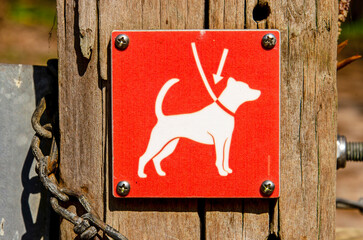 Oostvoorne, The Netherlands, April 4, 2025: Red sign on a hiking trail in the dunes indicating that dogs must be kept on a leash