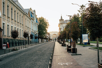 Empty city street with benches and trees at sunrise