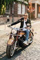 Stylish biker riding vintage motorcycle in city street