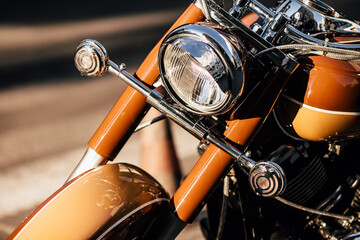 Shiny chrome headlight and orange fuel tank of motorcycle