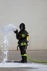 firefighter with big fire hose and white foam and protective helmet and breathing apparatus oxygen tank