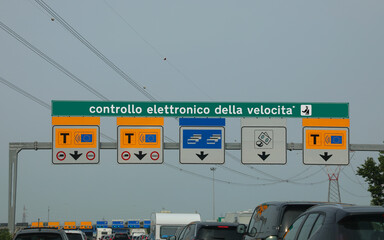 cars in the italian motorway and gate with text that means electronic speed  control