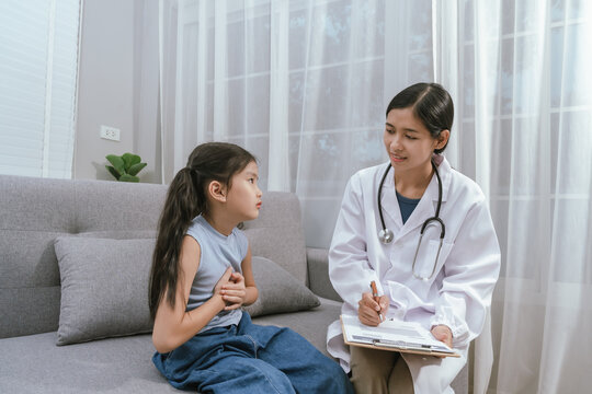 A smiling doctor examines a cute little girl at home, providing gentle care and health advice in a warm atmosphere. - Powered by Adobe
