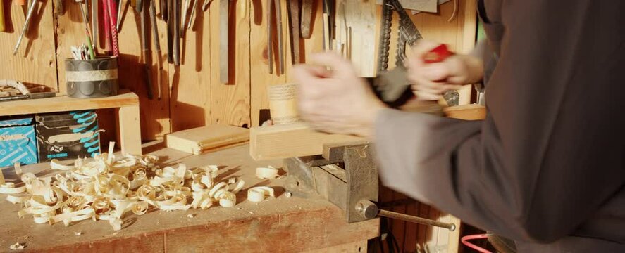Falegname rifinisce pezzo di legno con pialletto o pialla
