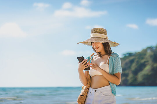 Happy asian traveler woman relax and use mobile phone for selfie on sea beach at day in Koh Kood Trat Thailand Travel summer holiday vacation concept