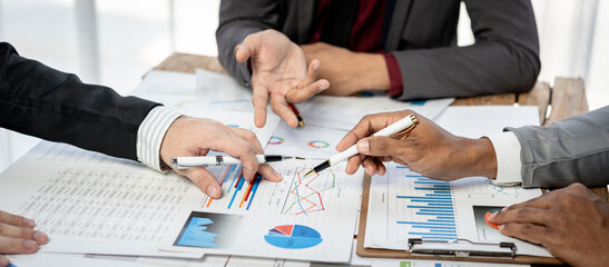 Three people are sitting at a table with papers and pens