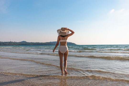 Happy traveler asian woman with white bikini relax on sea Klong Rahan beach in sunset at Koh Kood Trat Thailand Summer travel holiday vacation concept