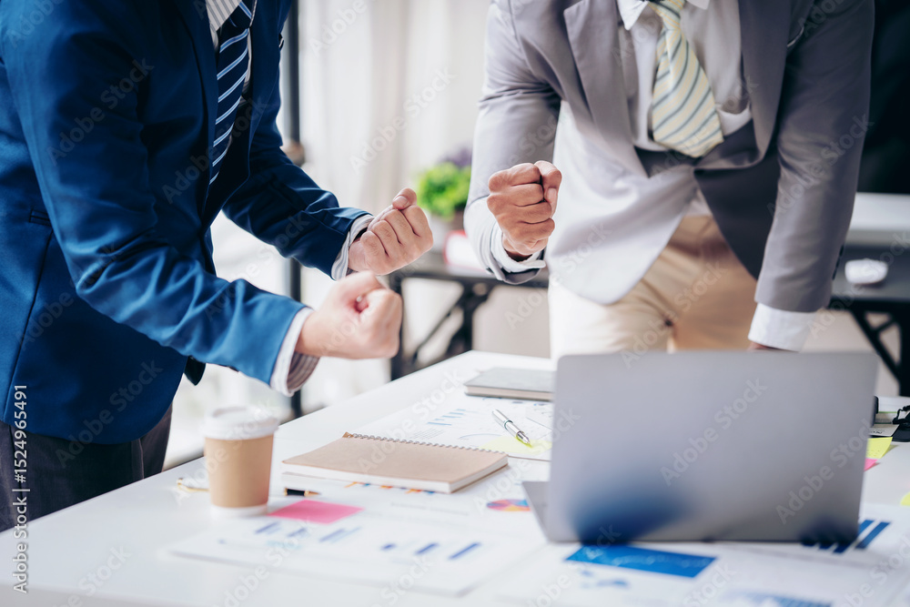 Poster two men are standing at a table with a laptop and papers