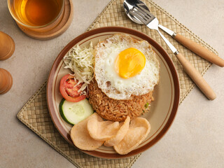 Fried rice with fried egg, vegetable salad and crackers on brown plate
