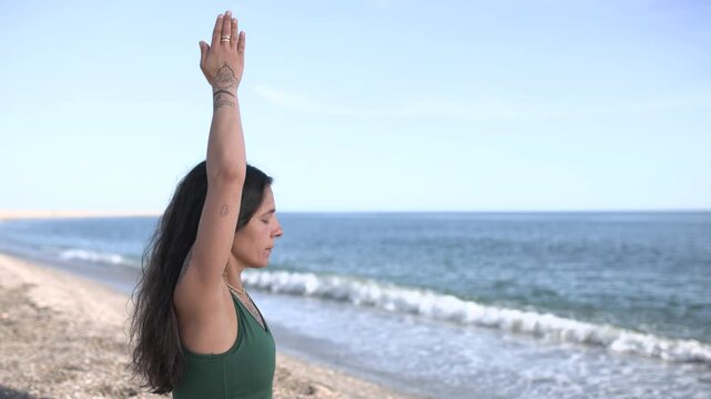 Woman practicing urdhva hastasana yoga pose on beach
