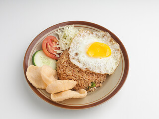 Fried rice with fried egg, vegetable salad and crackers on brown plate