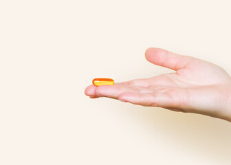 Hand Holding a Golden Omega-3 Fish Oil Capsule