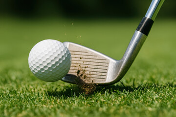 Close-up of a golf club striking a ball on a lush green course.