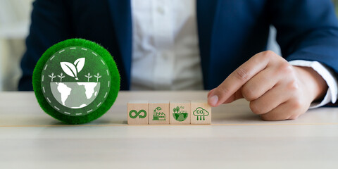 Corporate Sustainability Strategy concept. A green globe icon and wooden blocks displaying symbols for circular economy, green industry, environmental preservation and carbon reduction.