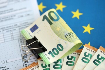 European euro currency money notes bunch on tax form and European union blue flag close up