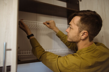 Carpenter installing dish rack in kitchen cabinet