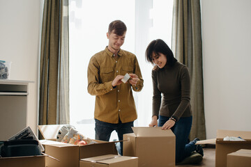 Young couple unpacking cardboard boxes in new home