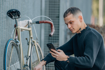 young man on the street looking at his mobile phone to repair the bicycle