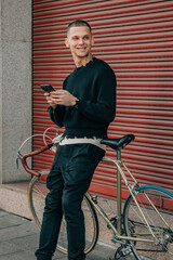 young man with mobile phone and bicycle on the street in red background