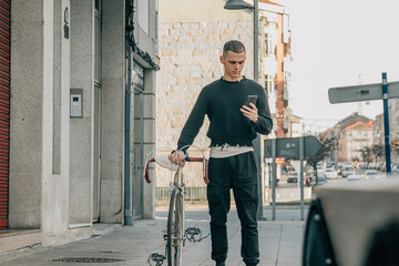 young man walking on the street with phone and bicycle