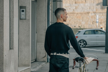 young man walking on the street with bicycle on his back