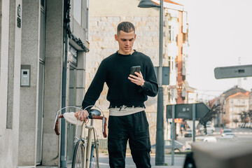 young man walking on the street with phone and bicycle