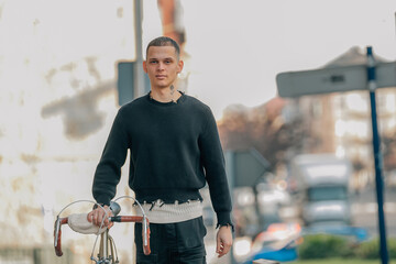 young man walking on the street with bicycle