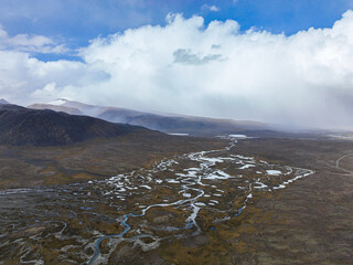 A sweeping aerial view captures a wide river delta with numerous streams and pools of water...