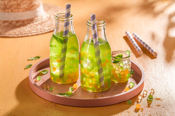 Fresh bubble tea with green and yellow balls with ice.