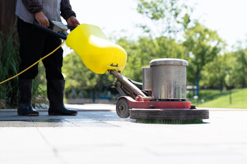 Workers are cleaning the road with a floor scrubber