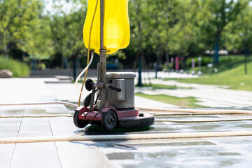 Workers are cleaning the road with a floor scrubber