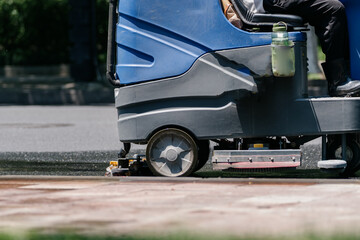 Workers are cleaning the road with a floor scrubber