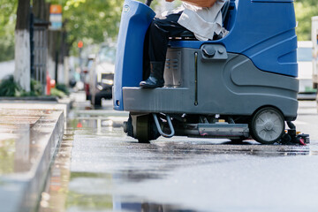 Workers are cleaning the road with a floor scrubber