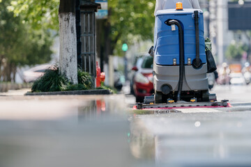 Workers are cleaning the road with a floor scrubber