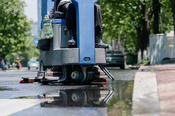 Workers are cleaning the road with a floor scrubber
