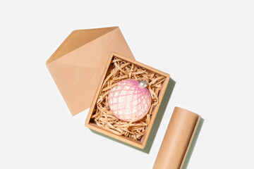 Eco-Friendly Christmas Composition With Christmas Ball In Kraft Paper Box, Wrapping Paper And Envelope For Sustainable Holiday Gifting, Eco Packaging, Conscious Shopping, And Christmas Decor Concepts